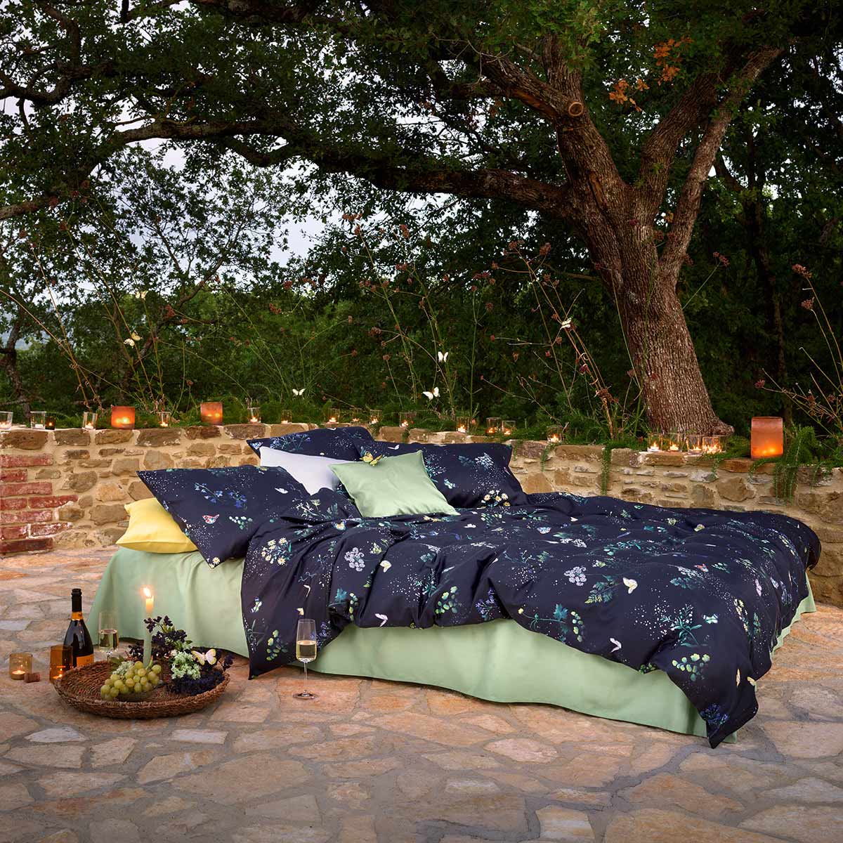 Ein gemütlicher Schlafplatz im Freien mit der Bettwäsche Mid Summer Night, dekoriert mit Lichtern und umgeben von Natur, ideal für eine romantische Sommernacht.