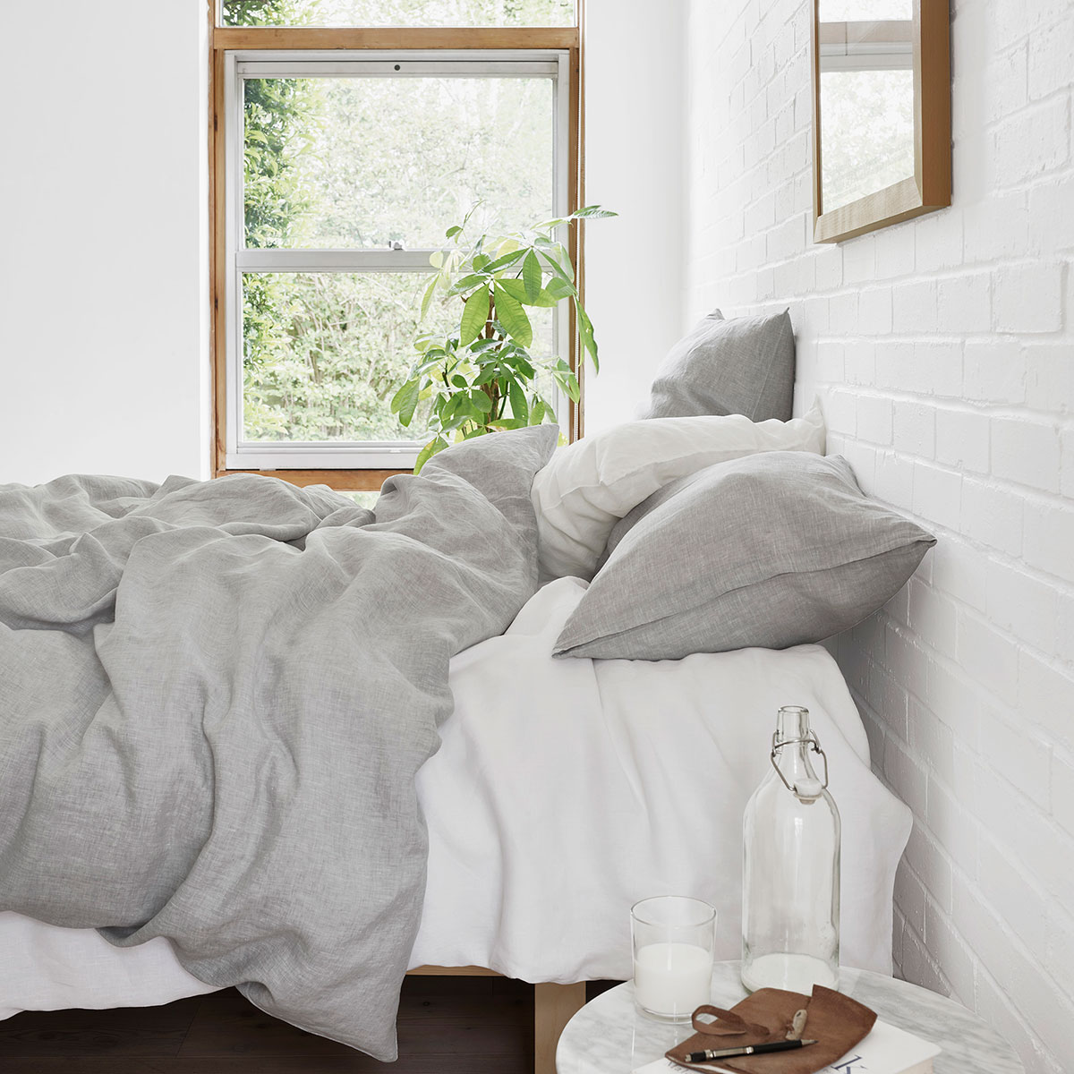 Schlafzimmer mit Levin Bettwäsche in Grau und Weiss Modernes Schlafzimmer mit Bett, das mit Levin Bettwäsche in Grau und Weiss bezogen ist, und einem Fenster im Hintergrund.