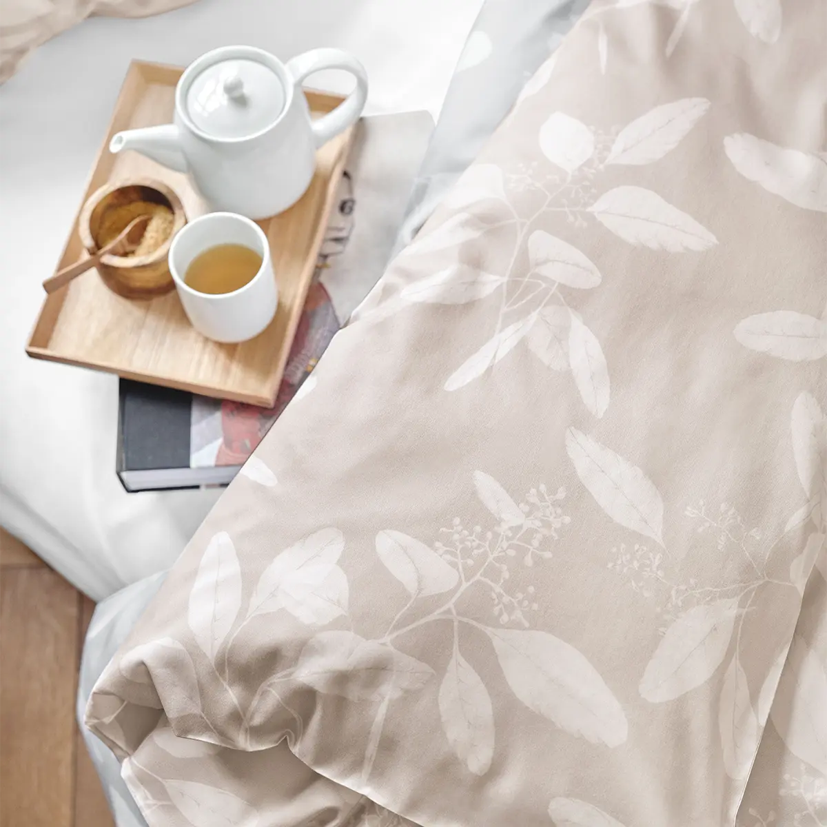 Omeo Bettwäsche - Entspannen mit Tee Eine Tasse Tee und eine Teekanne auf einem Tablett, arrangiert auf der beige-farbenen Omeo Bettwäsche mit Blättermuster.