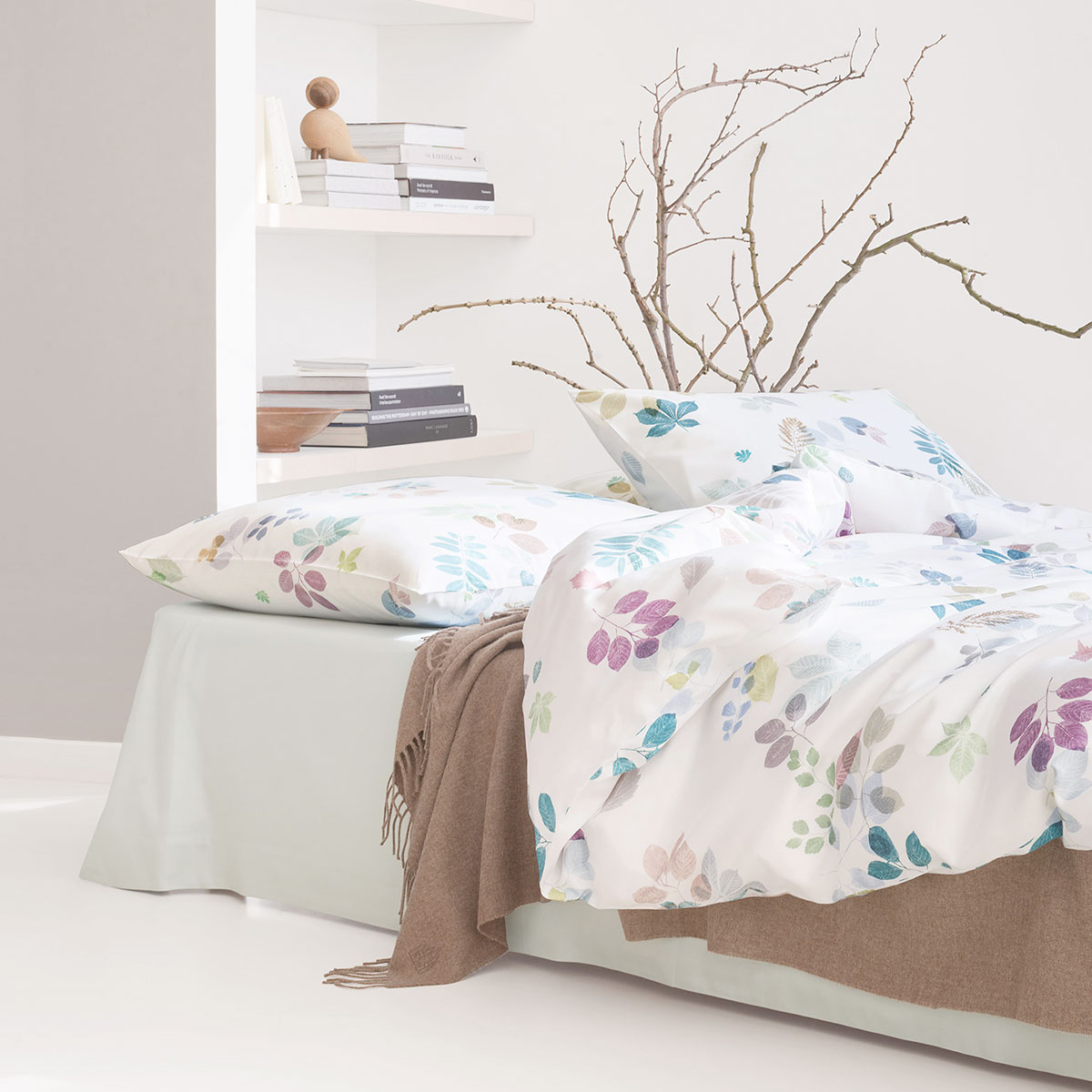 Eliv Bettwäsche im Schlafzimmer Schlafzimmer mit Eliv Bettwäsche Set, dekoriert mit Blättermuster in Pastellfarben, ergänzt durch neutrale Akzente und einen gemütlichen Zweig im Hintergrund.