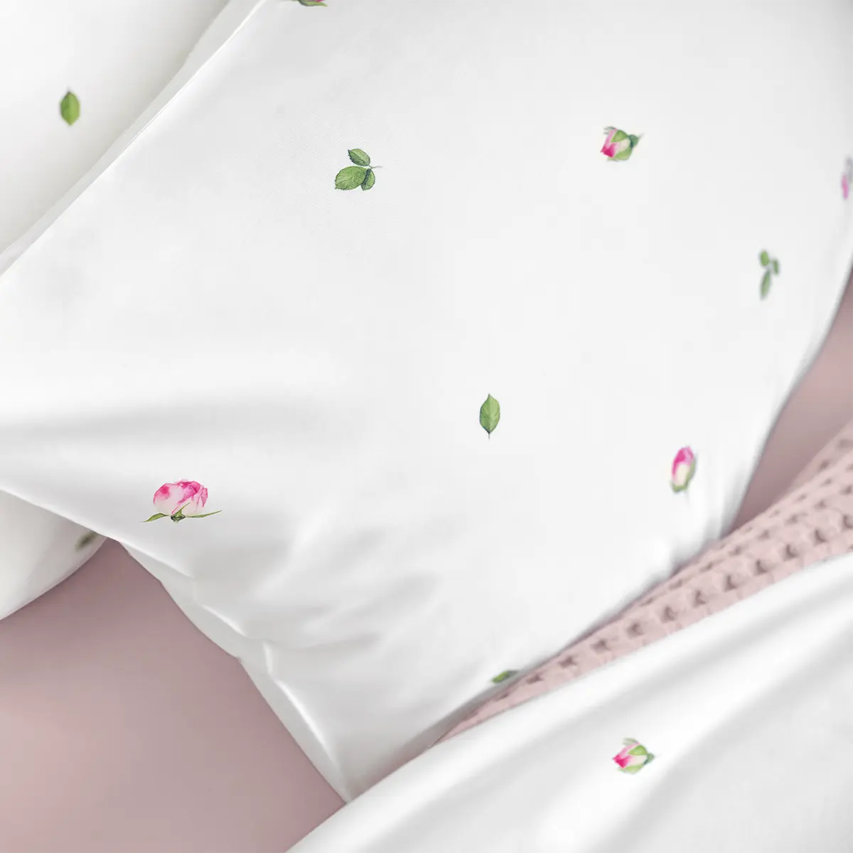 Elegante Jeunesse-Bettwäsche mit floralem Muster Weisse Kissen der Jeunesse-Bettwäsche, geschmückt mit rosa Blütenknospen und grünen Blättern, ideal für eine romantische Schlafzimmergestaltung.