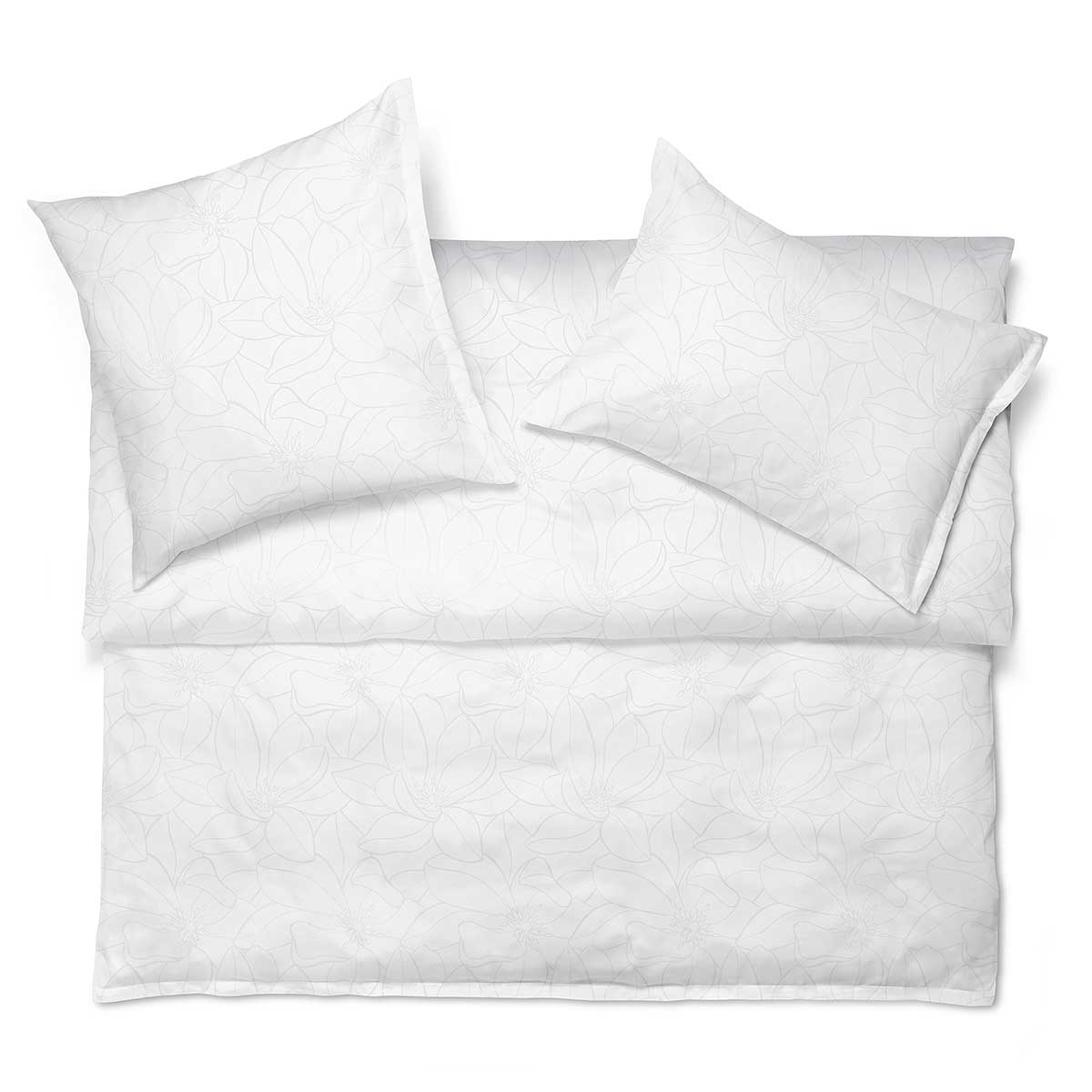 Magnolia Bettwäsche Set in Weiss auf einem Bett Bettwäsche Set Magnolia in Weiss mit dezentem floralem Muster, arrangiert auf einem Bett.