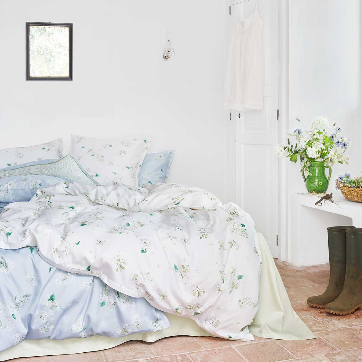 Schlafzimmer mit Bettwäsche May in Weiss Ein gemütliches Schlafzimmer dekoriert mit der Bettwäsche May in Weiss, kombiniert mit blauen Akzenten und einem natürlichen, hellen Ambiente.
