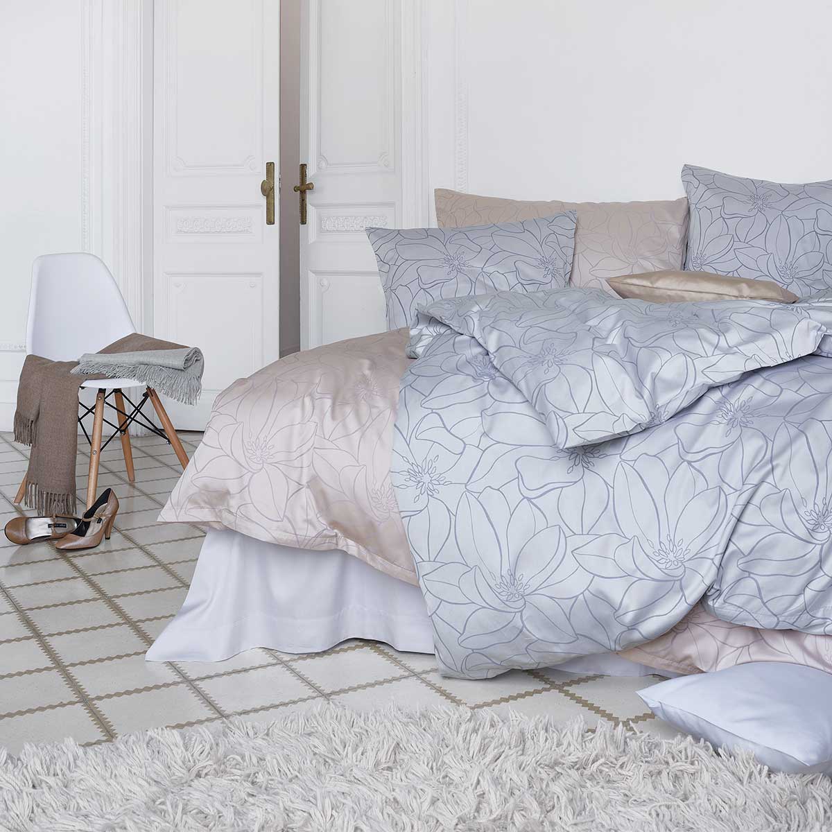 Schlafzimmer mit Magnolia Bettwäsche in verschiedenen Farben Elegantes Schlafzimmer mit Bett, bezogen mit Magnolia Bettwäsche in Grau und Beige, und dekoriert mit passenden Kissen.