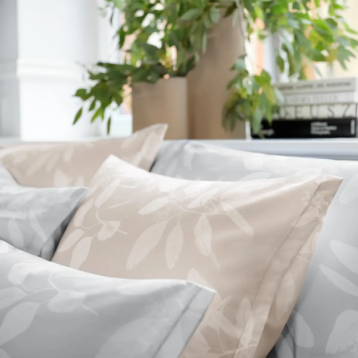 Omeo Bettwäsche - Dezente Eleganz Kissen der Omeo Bettwäsche in Beige und Grau, mit einem dezenten Blättermuster, dekorativ im Wohnzimmer platziert.