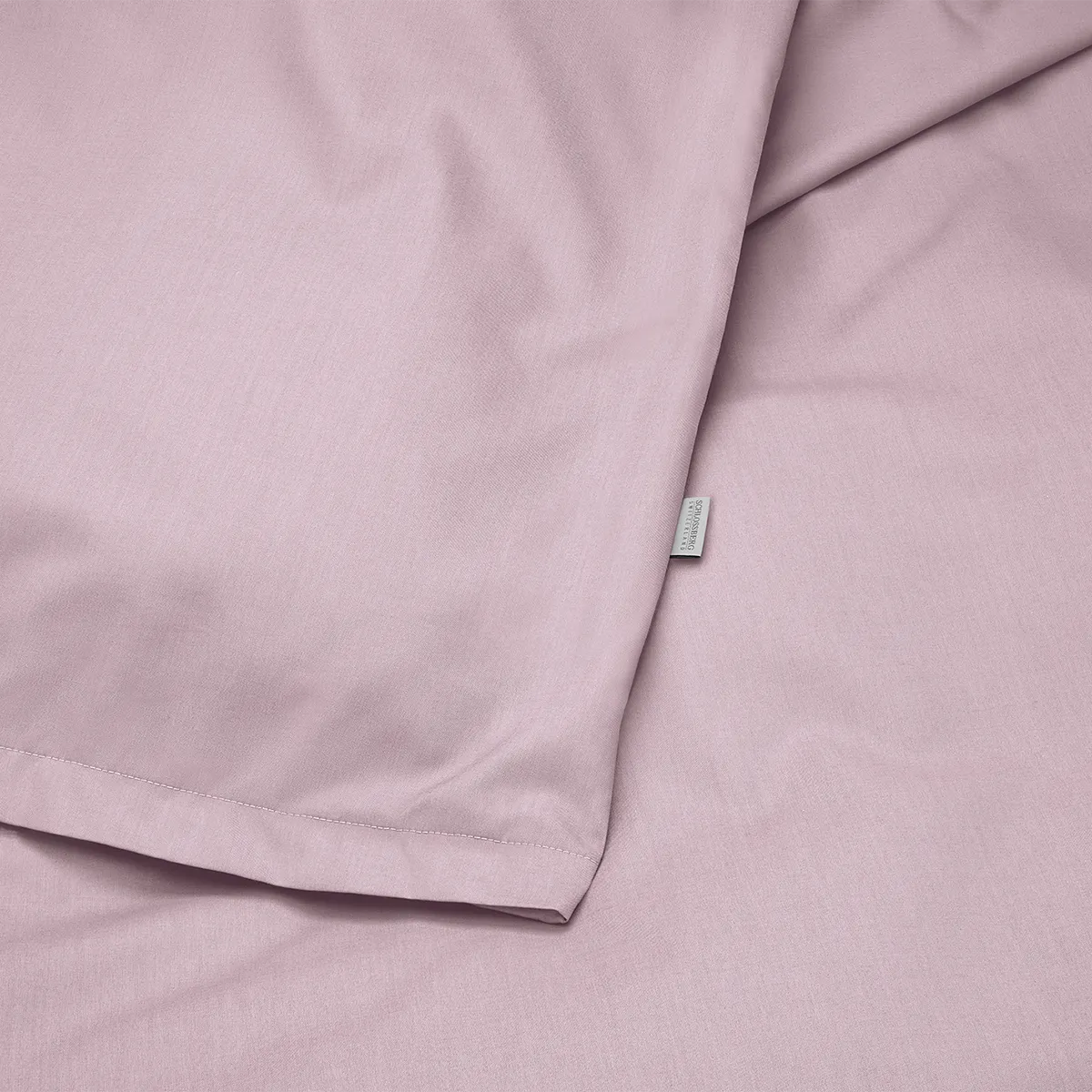 Nahaufnahme der Schlossberg Bettwäsche Ben Mauve mit feiner, hochwertiger Webstruktur. Der sanfte Mauve-Ton verleiht dem Stoff eine elegante und moderne Optik.