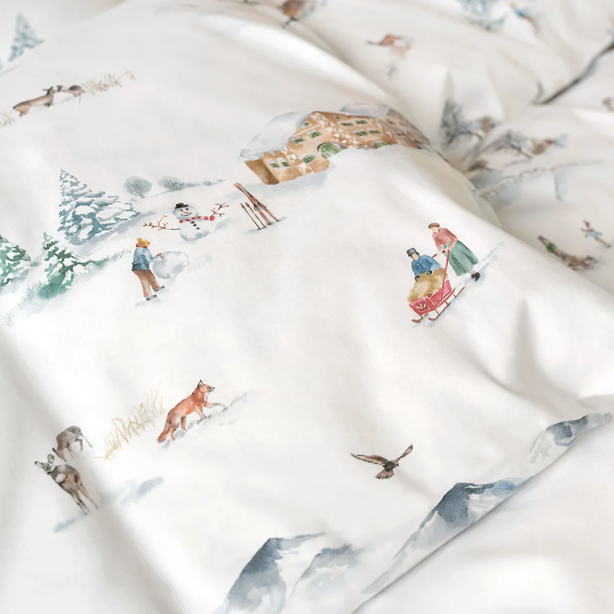 Montagne Bettwäsche - Detailaufnahme Winterlandschaft Nahaufnahme der Montagne Bettwäsche mit einem winterlichen Bergmotiv, inklusive Schneemann, Schlitten und Tieren.