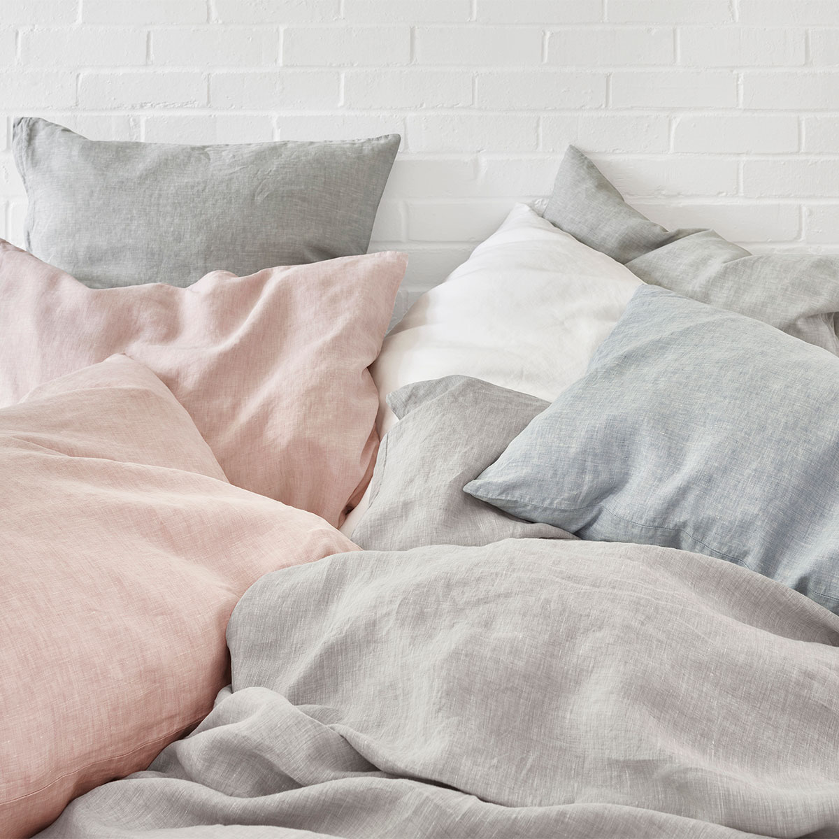 Levin Bettwäsche in verschiedenen Farben Bett mit Kissen in verschiedenen Farben der Levin Bettwäsche, darunter Rosa, Grau, Blau und Weiss.