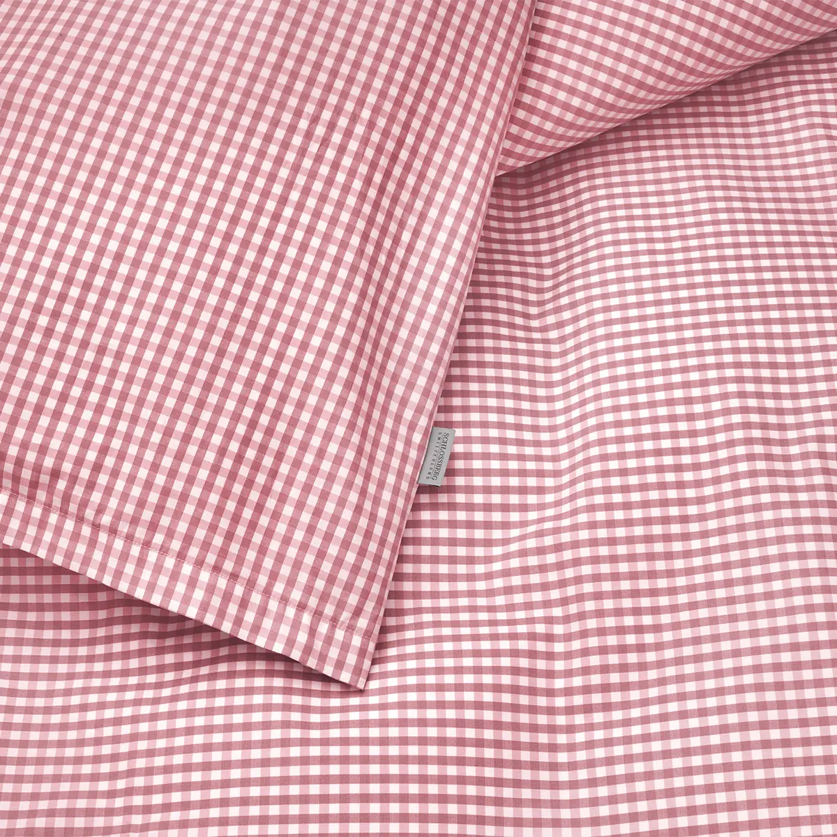 Die Detailansicht der Schlossberg Bettwäsche Andrin Rouge zeigt das charmante Karomuster in Rot- und Weißtönen. Die hochwertige Baumwolle sorgt für ein angenehmes Schlafgefühl und macht das Design zu einem stilvollen Highlight in Ihrem Schlafzimmer.