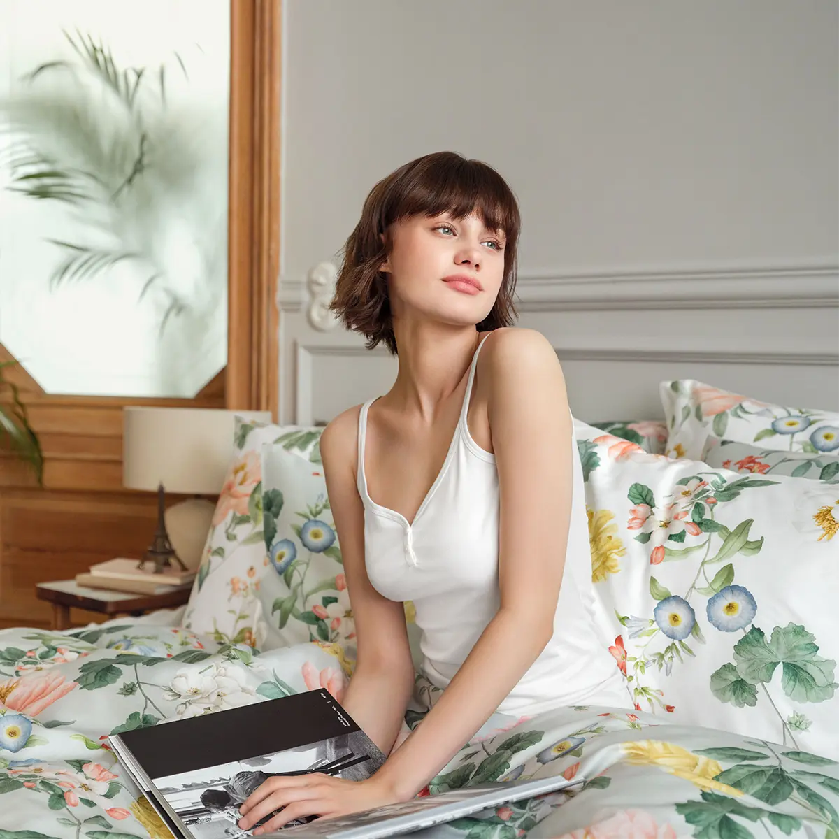 Bettwäsche Artemis in einem stilvoll eingerichteten Schlafzimmer mit einer Frau, die ein Buch liest.