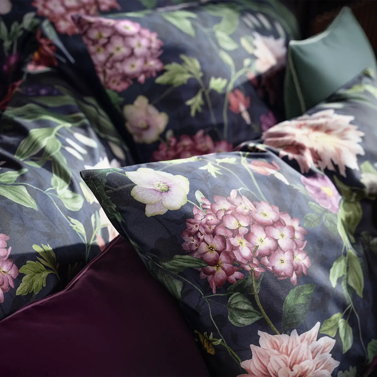 Nahaufnahme eines Kopfkissens mit dem dunkelblauen, floralen Muster der Ophelia Bettwäsche, das zarte Blüten in Violett und Rosa zeigt.